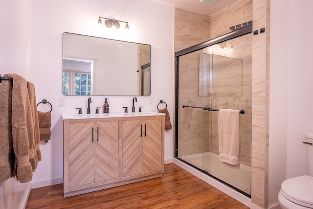 bathroom featuring a shower with door, hardwood / wood-style flooring, vanity, and toilet