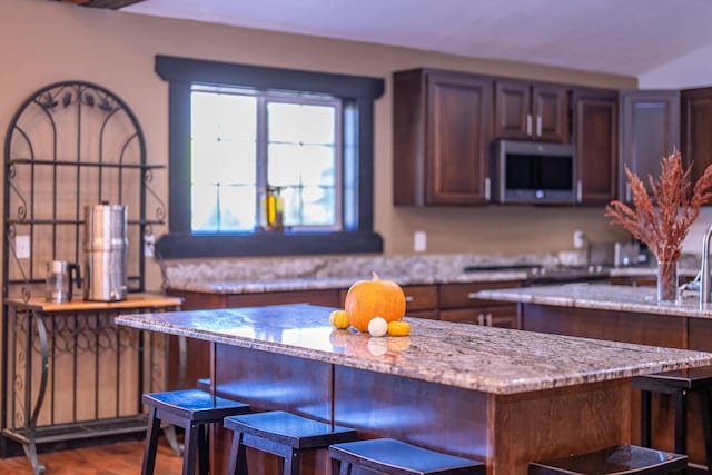 44 Copper Ridge Rd, Trout Creek, MT 59874 - kitchen with dark wood finished floors, stainless steel microwave, light stone countertops, a kitchen island, and a breakfast bar area
