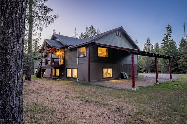 back house at dusk with a yard and a balcony