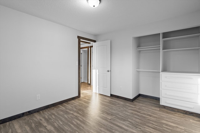 unfurnished bedroom featuring a textured ceiling, dark hardwood / wood-style floors, and a closet