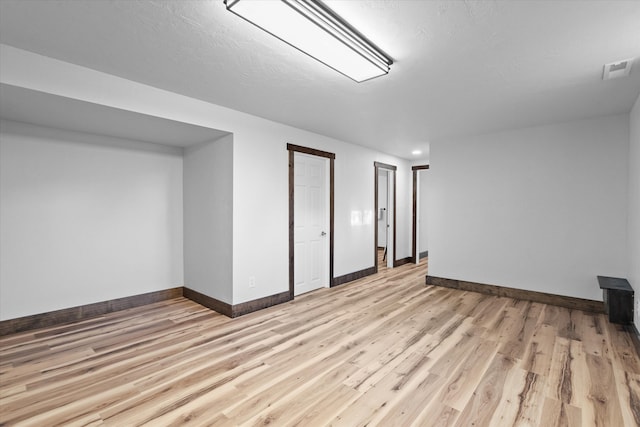 basement with light hardwood / wood-style flooring and a textured ceiling