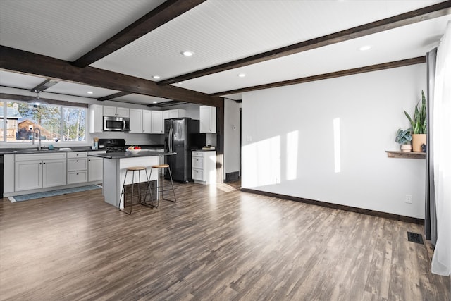 kitchen featuring dark wood-type flooring, black appliances, a kitchen island, a kitchen bar, and white cabinetry