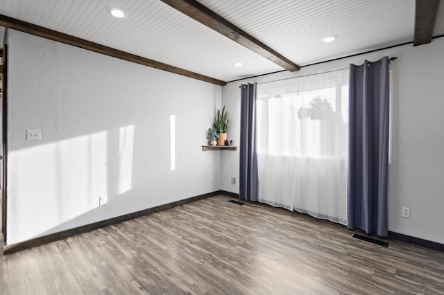 spare room with beam ceiling and hardwood / wood-style flooring