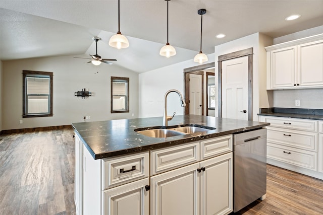 kitchen with dishwasher, white cabinets, vaulted ceiling, sink, and a kitchen island with sink