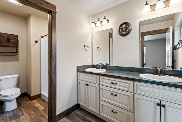 bathroom with toilet, vanity, a shower, and wood-type flooring