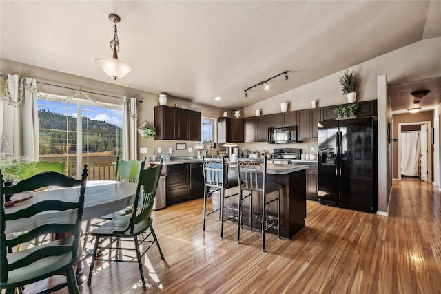 28 W Ashley Hills Dr, Kalispell, MT 59901 - kitchen featuring black appliances, dark brown cabinetry, light wood-style flooring, a center island, and lofted ceiling