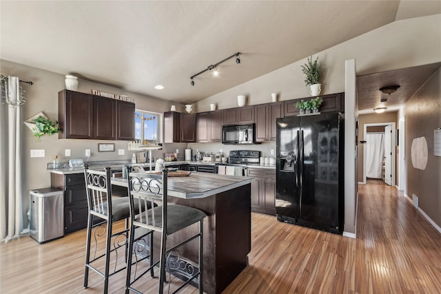 28 W Ashley Hills Dr, Kalispell, MT 59901 - kitchen with black appliances, dark brown cabinets, light wood-style flooring, a center island, and lofted ceiling