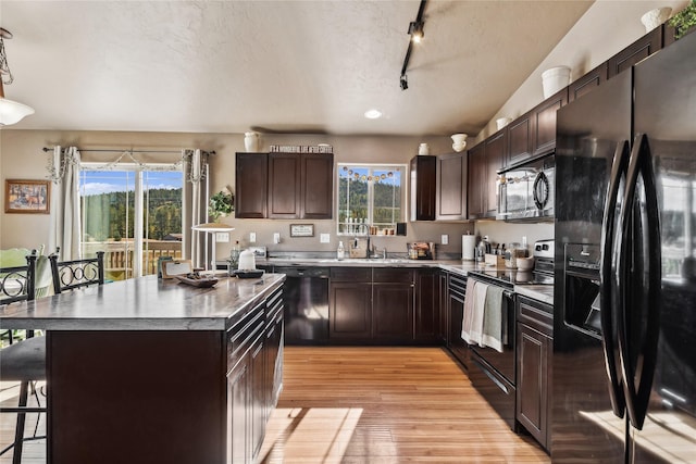 28 W Ashley Hills Dr, Kalispell, MT 59901 - kitchen with black appliances, a kitchen breakfast bar, light wood-type flooring, a center island, and track lighting