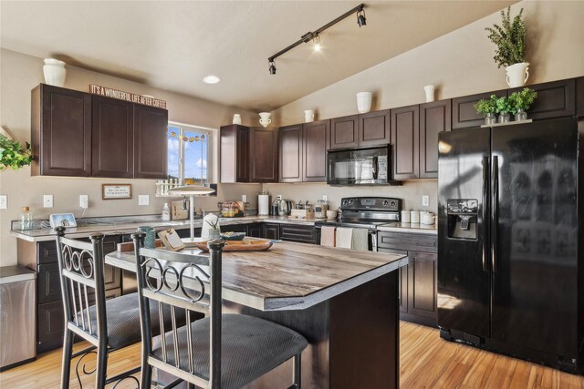 28 W Ashley Hills Dr, Kalispell, MT 59901 - kitchen featuring black appliances, rail lighting, dark brown cabinetry, light wood-style floors, and a breakfast bar area