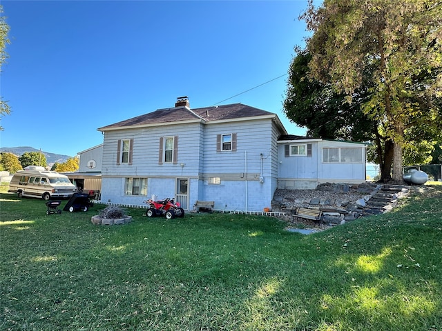 rear view of house with a mountain view and a lawn