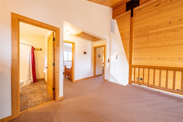 additional living space featuring light carpet, beamed ceiling, wood walls, and wooden ceiling