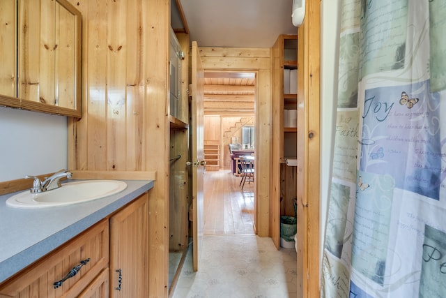 bathroom featuring hardwood / wood-style floors, wood walls, and vanity