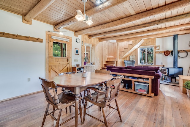 dining space with wooden walls, beamed ceiling, wood ceiling, and hardwood / wood-style floors