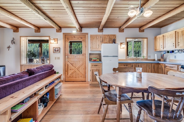 dining room with light wood-type flooring, beam ceiling, and wooden ceiling