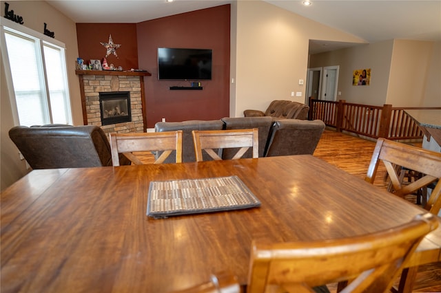 dining space with light hardwood / wood-style floors, a fireplace, and vaulted ceiling