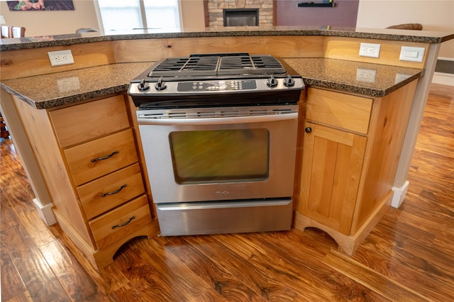 kitchen with gas stove, dark stone countertops, and hardwood / wood-style floors