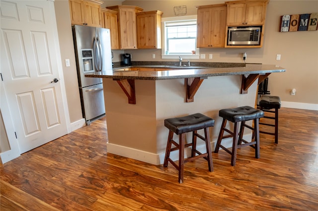 kitchen featuring a kitchen breakfast bar, dark hardwood / wood-style flooring, a kitchen island, and appliances with stainless steel finishes