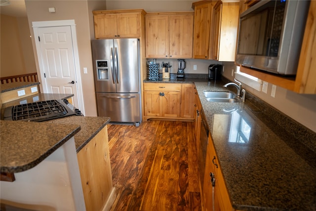 kitchen with dark stone counters, dark wood-type flooring, sink, and stainless steel appliances