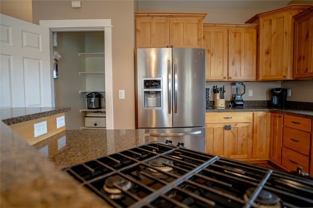 kitchen featuring stainless steel fridge, black gas cooktop, and dark stone counters