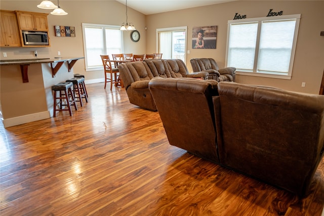 living room featuring dark hardwood / wood-style flooring, vaulted ceiling, and a notable chandelier