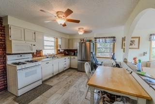 kitchen with arched walkways, white appliances, light wood-style flooring, and white cabinetry