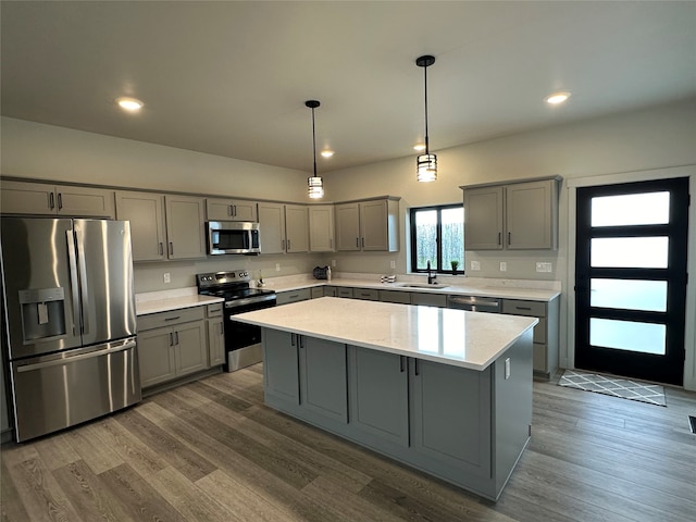 kitchen featuring dark wood-type flooring, hanging light fixtures, a center island, gray cabinets, and appliances with stainless steel finishes