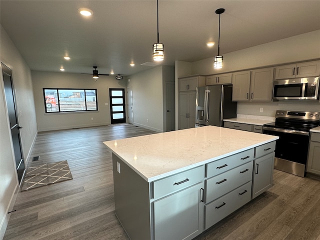 kitchen with appliances with stainless steel finishes, gray cabinetry, hanging light fixtures, and a kitchen island