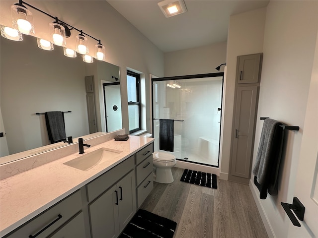 bathroom with toilet, hardwood / wood-style floors, walk in shower, and vanity