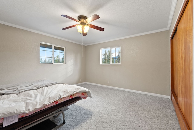 bedroom with ceiling fan, a closet, crown molding, carpet floors, and a textured ceiling