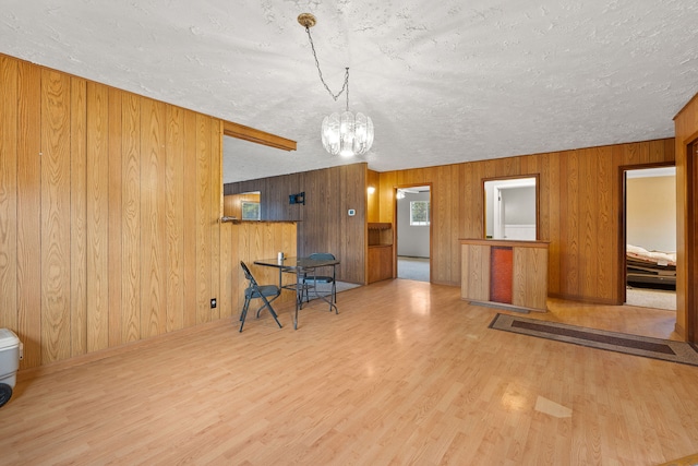 living room featuring an inviting chandelier, wood walls, hardwood / wood-style floors, and a textured ceiling