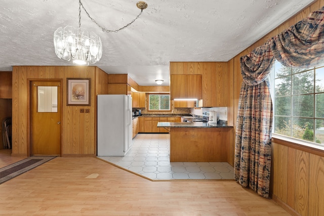 kitchen featuring kitchen peninsula, light wood-type flooring, white fridge, and a wealth of natural light