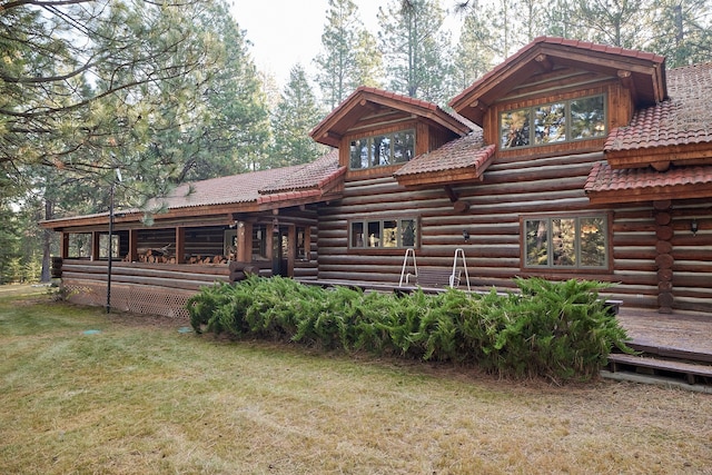 back of property featuring a wooden deck and a lawn