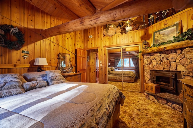 carpeted bedroom with wood ceiling, wood walls, beam ceiling, a stone fireplace, and a high ceiling