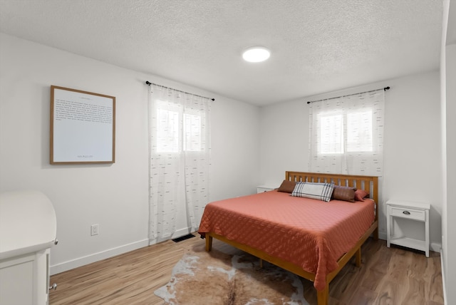 bedroom with a textured ceiling and light hardwood / wood-style flooring