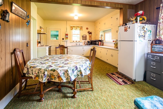 dining space featuring dark colored carpet and wooden walls