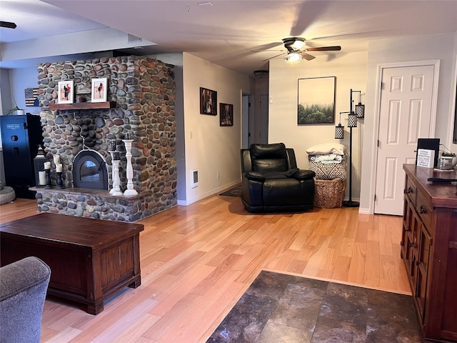 living room featuring a fireplace, light hardwood / wood-style floors, and ceiling fan