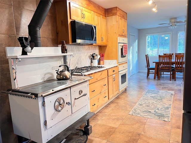 kitchen featuring light tile patterned floors, ceiling fan, appliances with stainless steel finishes, light brown cabinetry, and decorative backsplash