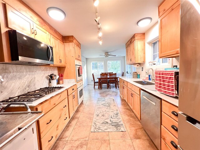 kitchen featuring sink, light tile patterned floors, appliances with stainless steel finishes, light brown cabinetry, and decorative backsplash