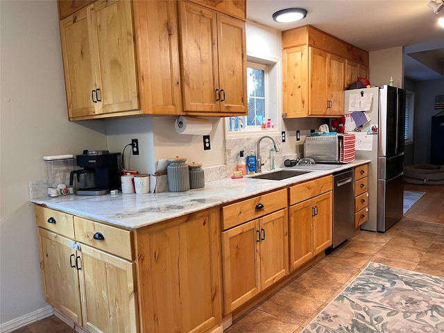 kitchen with stainless steel appliances, light stone countertops, and sink