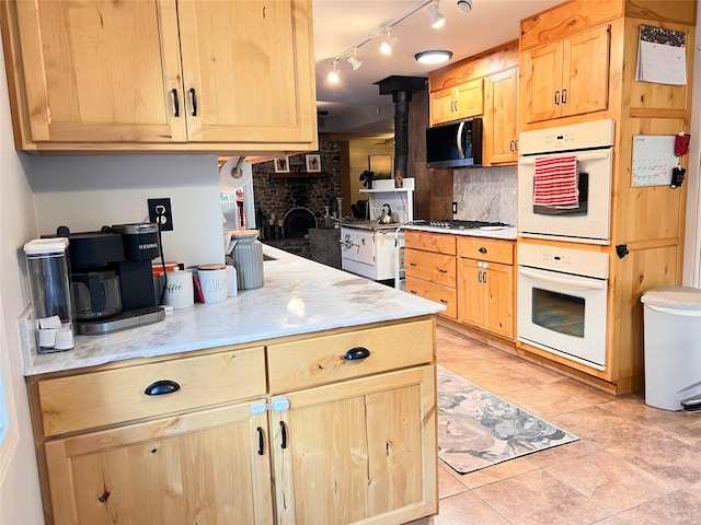 kitchen featuring a large fireplace, white double oven, decorative backsplash, and light brown cabinets