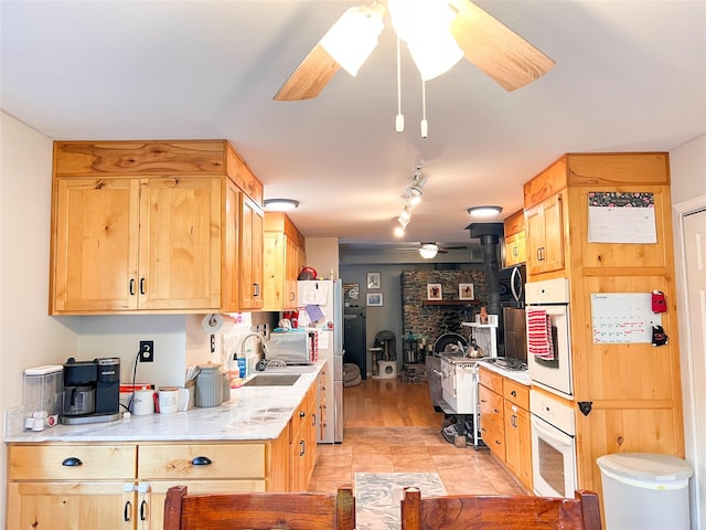 kitchen with ceiling fan, oven, sink, and light brown cabinets