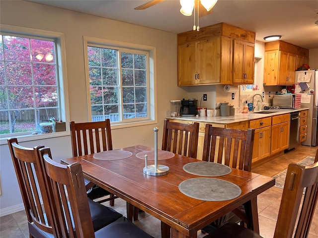 dining room with sink, light tile patterned flooring, a healthy amount of sunlight, and ceiling fan