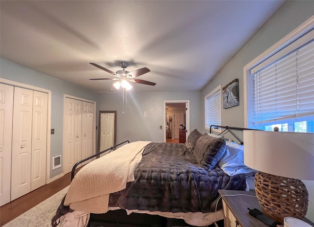 bedroom featuring multiple closets, ceiling fan, and dark hardwood / wood-style floors