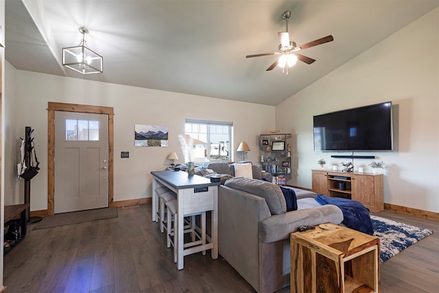 living room featuring vaulted ceiling, ceiling fan with notable chandelier, and dark wood-type flooring