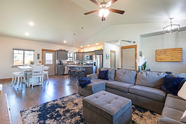 living room featuring ceiling fan with notable chandelier, lofted ceiling, and dark hardwood / wood-style flooring