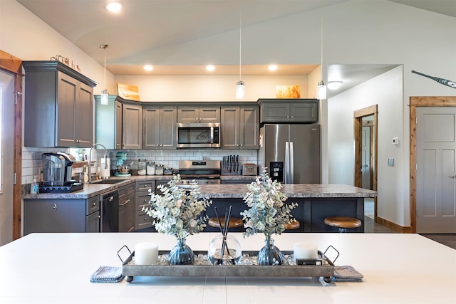 kitchen with lofted ceiling, hanging light fixtures, appliances with stainless steel finishes, and sink