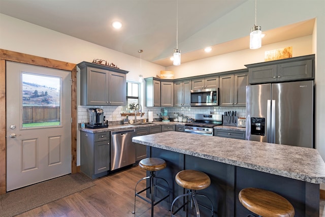 kitchen with tasteful backsplash, a breakfast bar, vaulted ceiling, stainless steel appliances, and hanging light fixtures