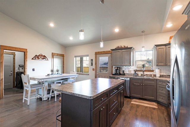 kitchen featuring a healthy amount of sunlight, decorative light fixtures, a center island, and dark hardwood / wood-style flooring