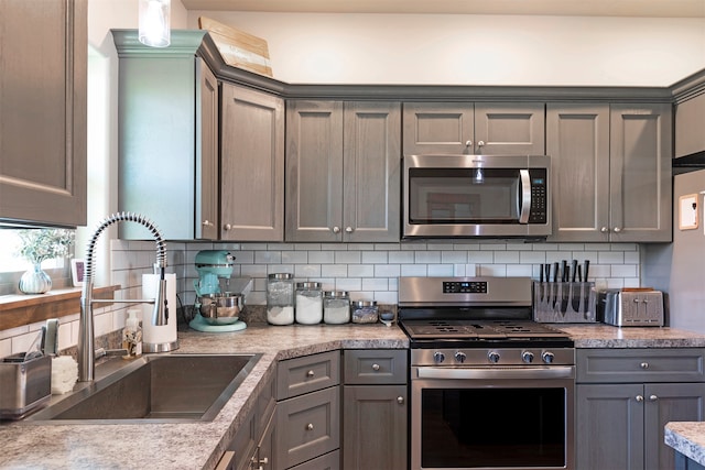 kitchen with backsplash, gray cabinets, appliances with stainless steel finishes, and sink