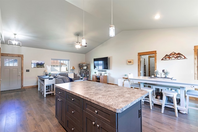 kitchen with ceiling fan, hanging light fixtures, a kitchen island, dark hardwood / wood-style floors, and vaulted ceiling